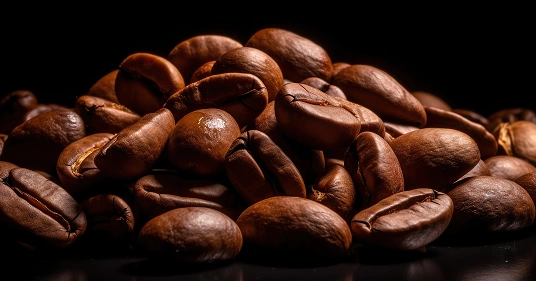 Close-up van glanzende, gebrande koffiebonen op een donkere achtergrond. De rijke bruine tinten en het glanzende oppervlak stralen warmte en rijkdom uit.